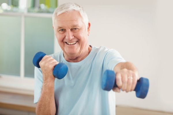 smiling white senior man exercising with dumbbells