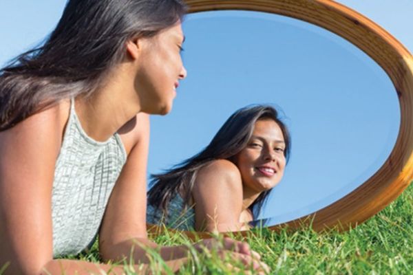 Smiling young girl looking at herself in a mirror