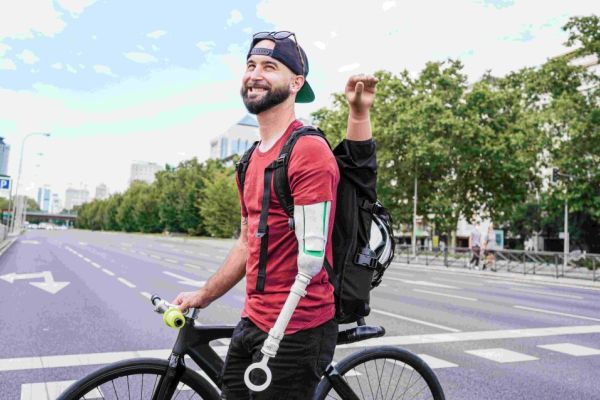 Smiling young male adult with upper limb custom cycling prosthesis with bicycle.