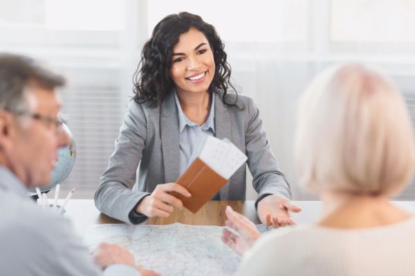 Smiling female travel agent at desk with clients
